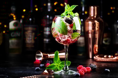 a glass of wine with berries and mint leaves de Lu Mezcal
