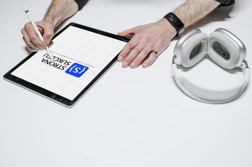 a man is writing on a tablet with a pen and headphones