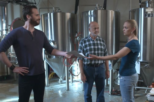 two men and woman standing in a brewery