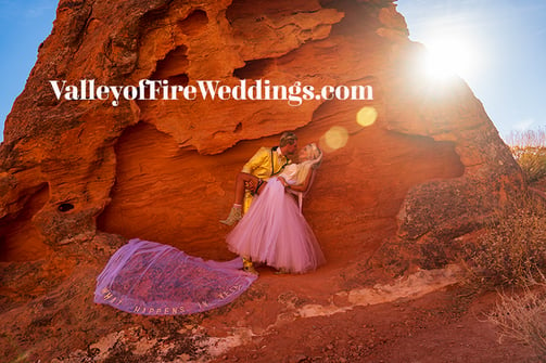 a man and woman kissing in front of a rock formation