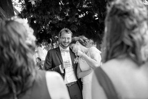 photo en noir et blanc de mariés riant devant leurs invités