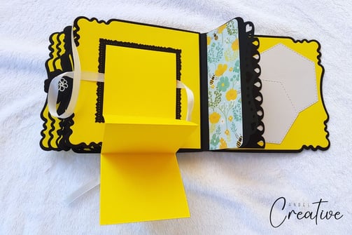 Handmade photo album with scalloped edges features bright yellow, black, and floral patterns. A whit