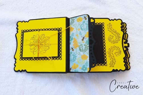 Elegant handmade photo album featuring yellow and black scalloped layers. Center has a floral illust