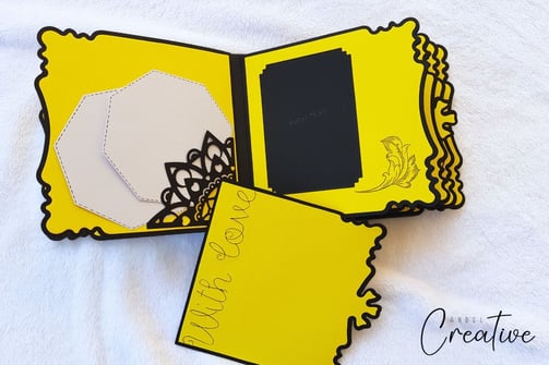 Bright yellow handmade album with scalloped edges, featuring black floral cutouts, a "With Love" mes