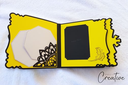 Open handmade album with a black and yellow theme on a white background. Left side features geometri