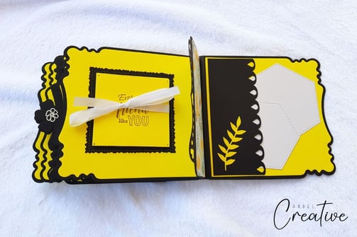 Handmade album with decorative yellow and black pages. The left page has a ribbon and text; the righ
