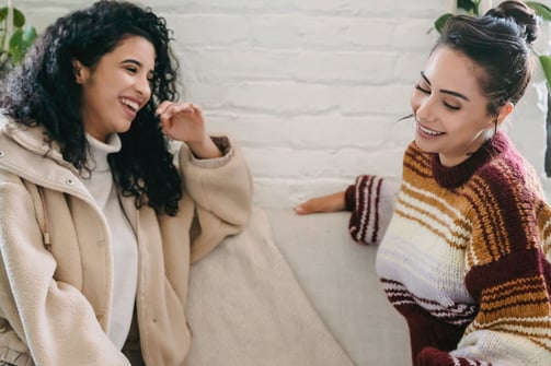 two women sitting on a couch in a living room