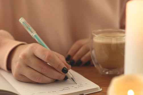 a person writing a notepad with a pen and a pen