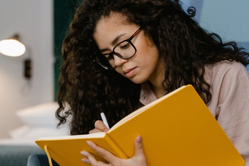 a woman sitting on a couch with a notebook and pen