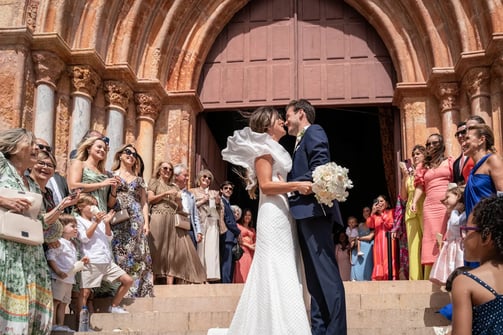 baiser des mariés sur le parvis d’une église, entourés d’une foule joyeuse et célébrante