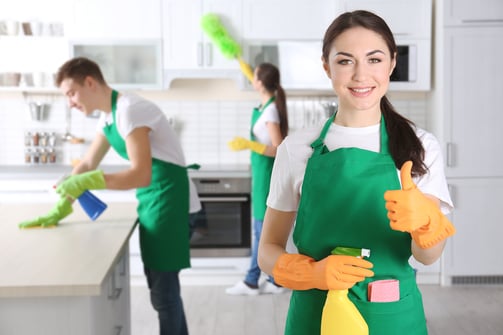 a woman in green aprons holding a cleaning sponge