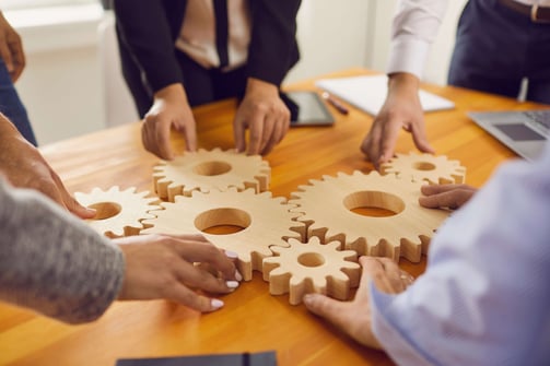 EMPRESÁRIO E COLABORADORES MONTANDO ENGRENAGENS