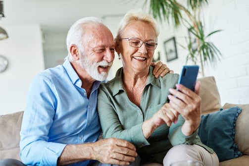 older couple smiling while looking at a smart phone