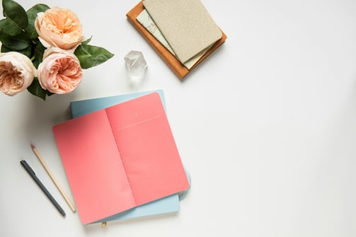 a desk with a notebook and a pen and a flower / un bureau avec un cahier, un stylo et une fleur