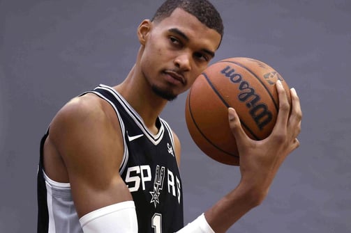 Victor Wembanyama posing with basketball in Spurs jersey