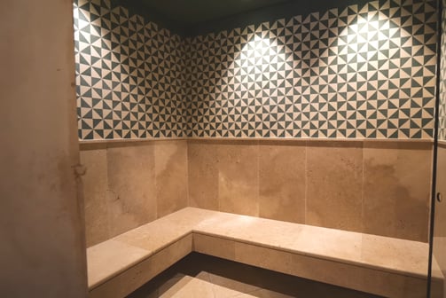 Steam room at Villa La Gratitud’s with geometric tile design and built-in stone bench.