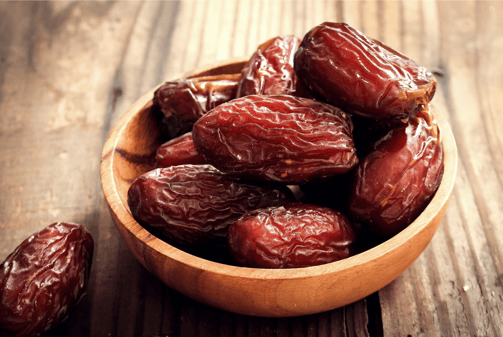 a bowl of dates in a wooden bowl