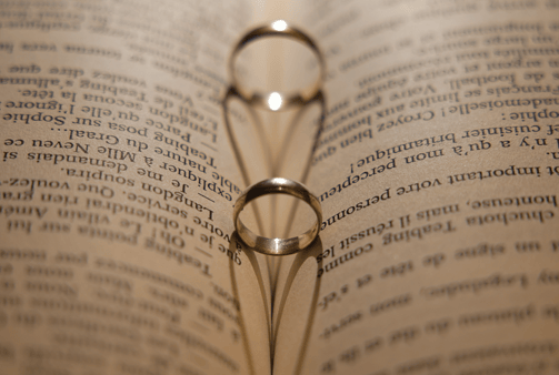 two wedding rings on a book with two rings on them