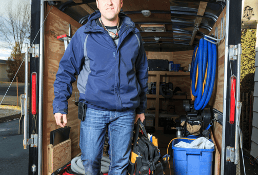 a man in a blue jacket is standing in front of a moving truck