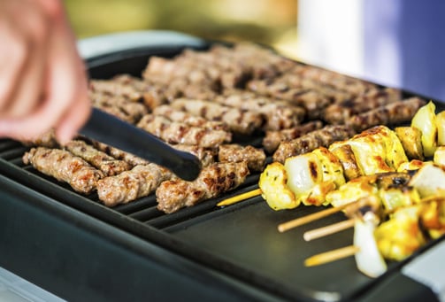 a person is cooking on a grill with skewers
