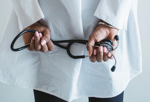Un medico sosteniendo el fonendo de espaldas.