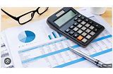 recordkeeping documents with financial information a calculator and a pair of glasses on a desk