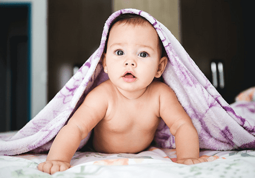 um bebê está deitado em uma cama com um cobertor