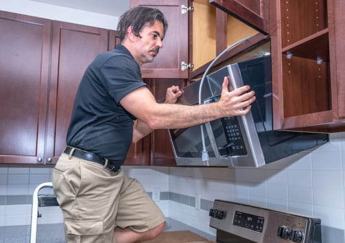 a man is standing in front of a microwave