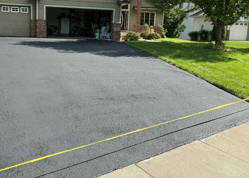 a driveway with fresh sealcoat blacktopping