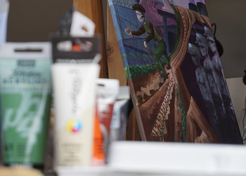 A painted canvas in a cubist or constructivist style depicting agriculture is displayed in focus.