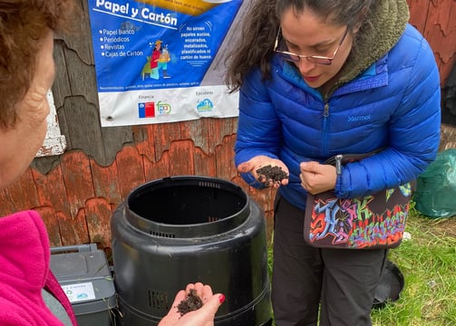 Equipo EcoRumbo enseñando a la comunidad uso de compostera en educación ambiental.