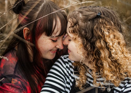 Zwei Frauen sitzen kuschelnd im Feld