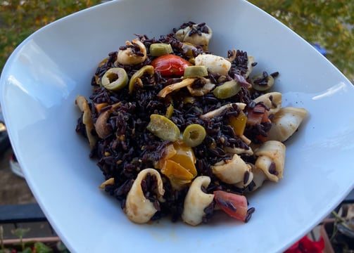 Riso venere nero ai frutti di mare, pomodorini e olive.
