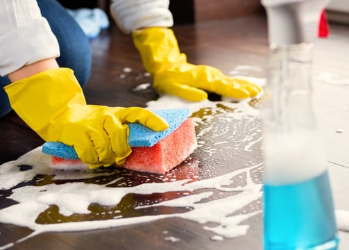 a person cleaning a wooden floor with a sponge pad