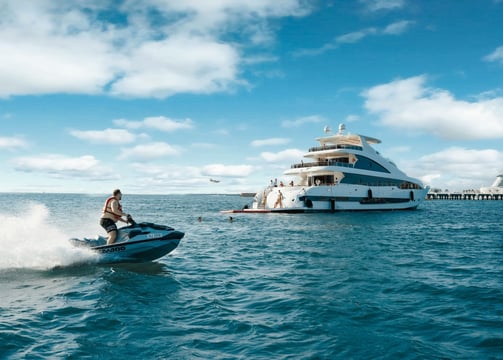Luxury yacht cruising through Dubai Marina lagoon with skyscrapers in the background and clear blue