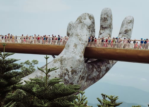 Golden Bridge in Vietnam held by giant stone hands, surrounded by misty hills and lush greenery.