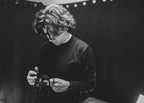 A man setting up a camera in a podcast studio.