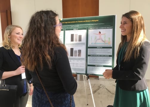 Dr. Grasser talks to two individuals about research on yoga, art, & dance interventions for families