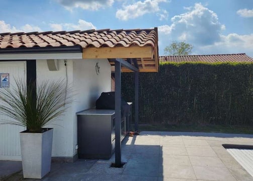 Structure métallique sur mesure pour cuisine extérieure avec auvent en tuiles, conçue par un métallier ferronnier à proximité