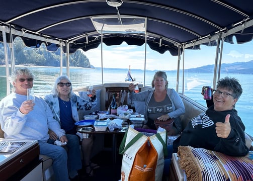 a group of people sitting on an eco-friendly all electric boat celebrating a birthday