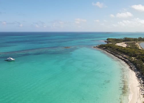a boat is sailing in the ocean near a beach