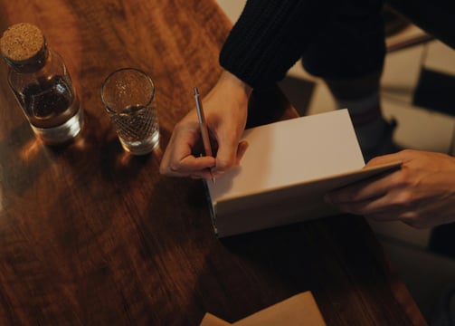 A picture of a man's hand preparing to sign the inside of a novel