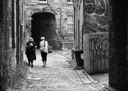 Two women, their back to camera, walk through Bread Street Lane, Edinburgh