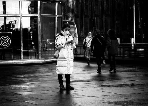 A woman tourist, wearing a face mask, stands at the West End, on her phone. Princes Street, Edinburgh