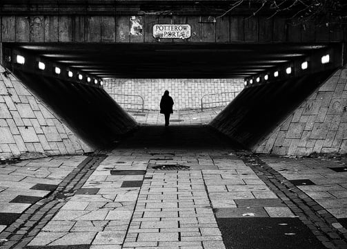 A solitary figure, in silhouette, walks through the underpass at Potterow, Edinburgh