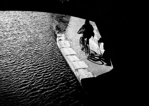 A cyclist on the canal emerges from a bridge in shadow into the light at Meggetland, Edinburgh