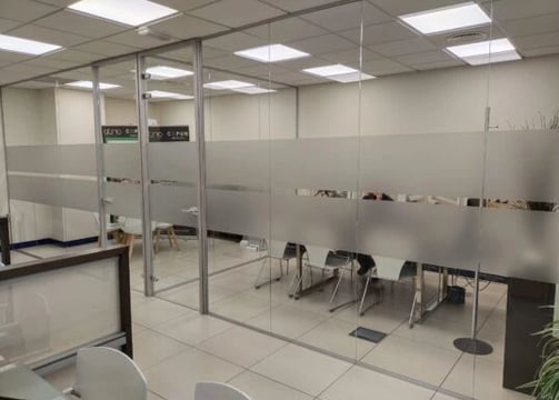 Divisorias para oficinas en cristal laminar de 5+5 mm. con puerta en vidrio templado de 10 mm. y lámina de vinilo opaca eca