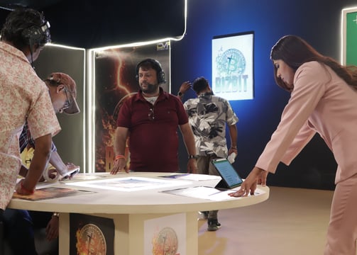 a woman in a pink suit is standing in front of a table with a laptop
