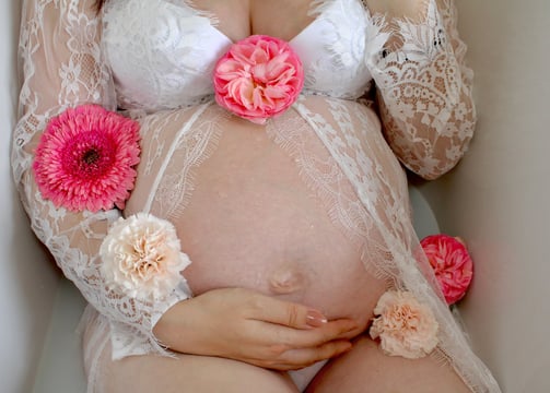 femme enceinte dans une baignoire pour séance photo avec bain de lait et fleur dans la baignoire