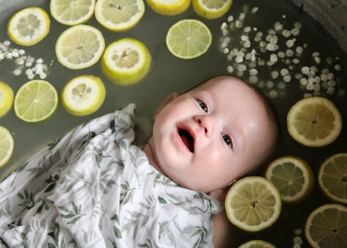 bain de lait bebe avec bebe entouré de citron et de fleurs ou d'autres fruits